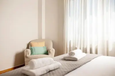 a bedroom with a chair and a bed with towels at Hospes - Chic retro retreat in the heart of Athens in Athens
