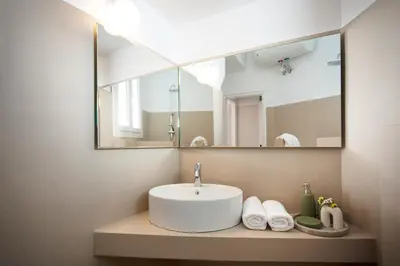 a bathroom with a sink and a large mirror at Hospes - Chic retro retreat in the heart of Athens in Athens
