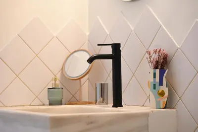a bathroom sink with a black faucet and a mirror at Stylish and spacious apartment in cool area in Athens