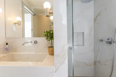 two images of a bathroom with a shower and a sink at The Mediterranean Suites in Piraeus