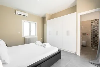 a bedroom with a large white bed and a bathroom at LIV - Sunny Penthouse Near Acropolis in Athens