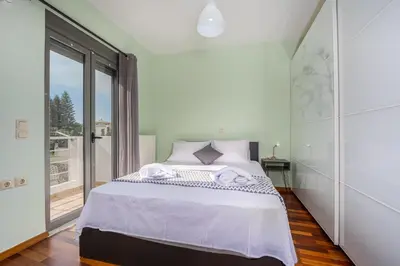 a white bedroom with a bed and a large window at Villa Galano - Your Cozy Retreat In The Athenian Riviera in Vari