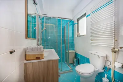 a blue tiled bathroom with a toilet and a shower at Villa Galano - Your Cozy Retreat In The Athenian Riviera in Vari