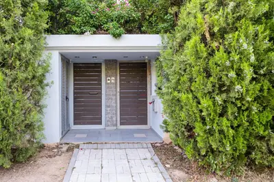 a garage with a door between two large bushes at Villa Galano - Your Cozy Retreat In The Athenian Riviera in Vari