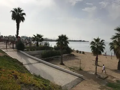 a person walking on a beach with palm trees at Flisvos Beach Studio in Athens