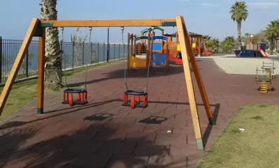 a playground with a swing set in a park at Flisvos Beach Studio in Athens