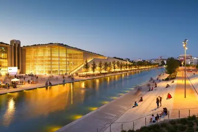 a river in a city with people walking on the sidewalk at Flisvos Beach Studio in Athens