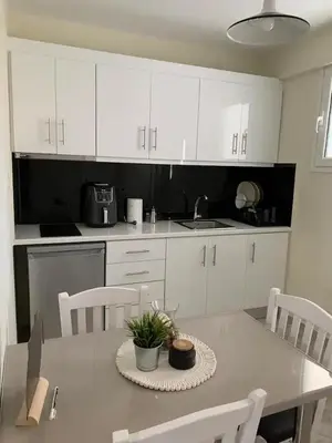 a kitchen with white cabinets and a table with a plant on it at Apartment near Piraeus port in Piraeus