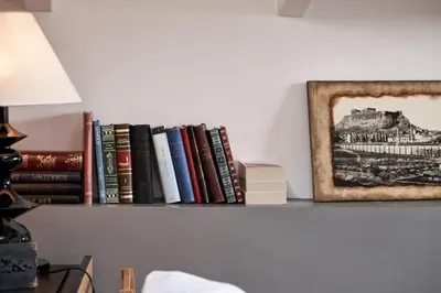 a shelf with books and a picture of a building at Emporikon Athens Hotel in Athens