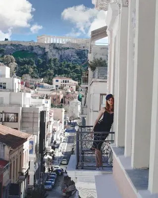 a woman standing on the balcony of a building at Emporikon Athens Hotel in Athens