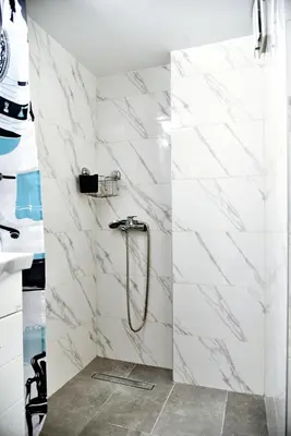 a bathroom with a shower with white marble tiles at Kipseli NEW MoDeRN & CoZy 65TV Netflix in Athens