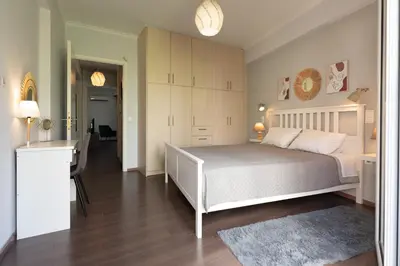 a bedroom with a large white bed and a hallway at Vibrant apartment next to Acropolis in Athens