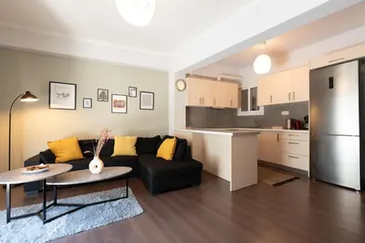 a living room with a black couch and a kitchen at Vibrant apartment next to Acropolis in Athens