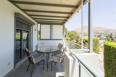 a patio with a table and chairs on a balcony at Luxury Holiday Home near the Sea in Kalívia Thorikoú
