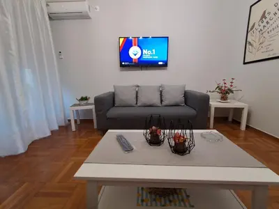 a living room with a couch and a tv on the wall at Urban Chic Flat Pagrati Athens in Athens