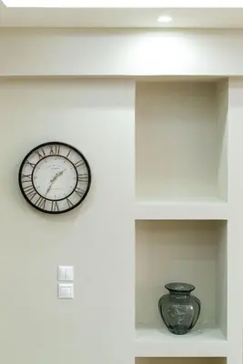 a clock on a wall with a vase on a shelf at Filoxenia MG projects Alimos in Athens