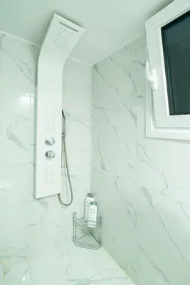 a white bathroom with a shower and a tv at Filoxenia MG projects Alimos in Athens