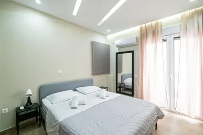 a bedroom with a white bed and a large window at Filoxenia MG projects Alimos in Athens