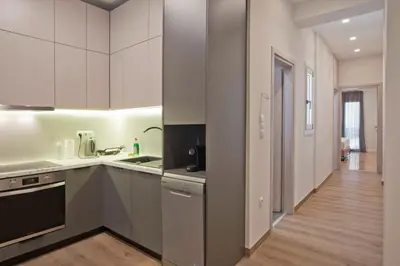 a kitchen with white cabinets and a wooden floor at Athenian Escape 2BR, 2BA, Stylish Fully Reno Apt in Athens