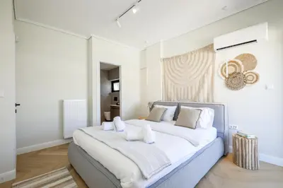 a large white bedroom with a large bed with white pillows at Glyfada Platinum Résidence in Athens