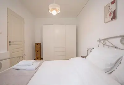 a white bedroom with a bed with white pillows at Lovely Cosy Apartment In Papagos in Athens