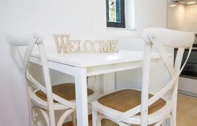 a white desk with two chairs in a room at Lovely Cosy Apartment In Papagos in Athens