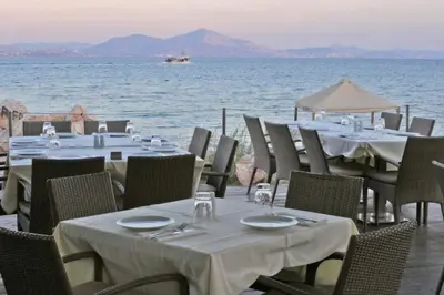a group of tables and chairs with a view of the ocean at R&G luxury accommodation Varkiza in Vari