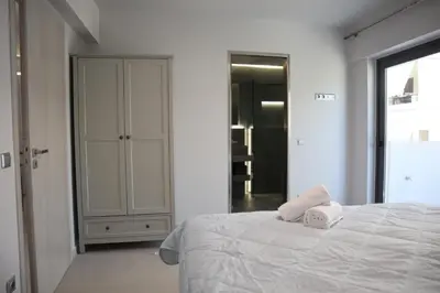 a white bedroom with a bed and a closet at Golden Sand Suites in Anavissos
