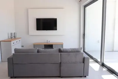 a living room with a couch and a tv at Golden Sand Suites in Anavissos
