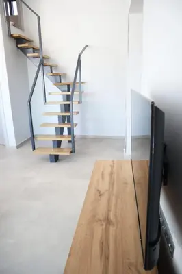 a tv sitting on a table next to a staircase at Golden Sand Suites 2 in Anavissos