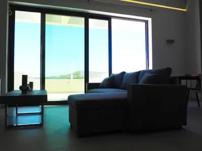 a living room with a couch and a table and windows at Golden Sand Suites 2 in Anavissos