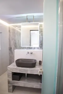 a bathroom with a black sink and a mirror at Golden Sand Suites 2 in Anavissos