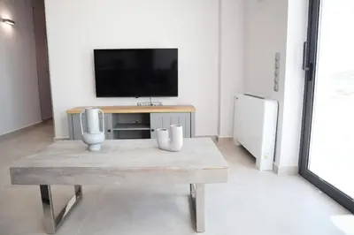 a living room with a table and a tv at Golden Sand Suites 2 in Anavissos