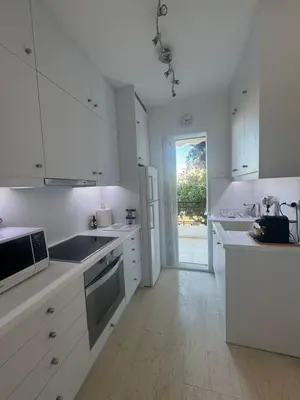 a white kitchen with a sink and a refrigerator at Artist Home in Porto Rafti