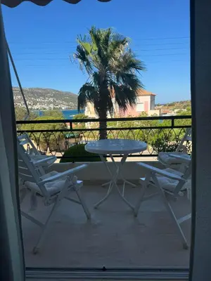 a table and chairs on a balcony with a palm tree at Artist Home in Porto Rafti
