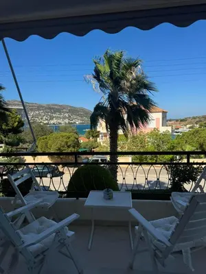 two chairs and a table on a balcony with a palm tree at Artist Home in Porto Rafti