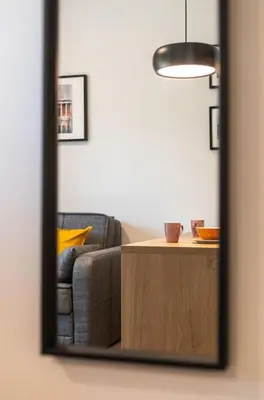 a mirror reflecting a living room with a couch and a table at The Meta Stay - Rooftop Access 1 bedroom suite in Athens