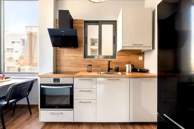 a kitchen with white cabinets and a sink and a table at Boutique39 Luxury Apartment Glyfada Athens in Athens