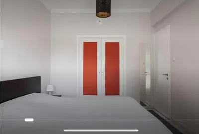 a white room with a bed and a red door at Beach of Voula in Athens