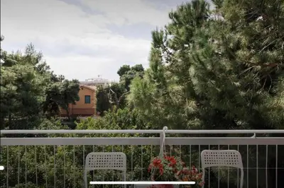 two white chairs on a fence with trees and a building at Beach of Voula in Athens