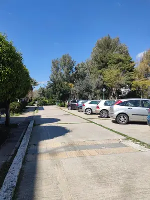 a street with cars parked on the side of the road at Beach of Voula in Athens