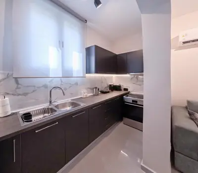 a kitchen with black cabinets and a sink at Katia Athens Apartment in Athens