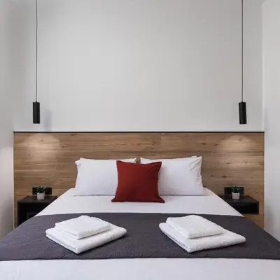 a bedroom with a white bed with two red pillows at The Meta Stay - Rooftop Access Unique Suite in Athens