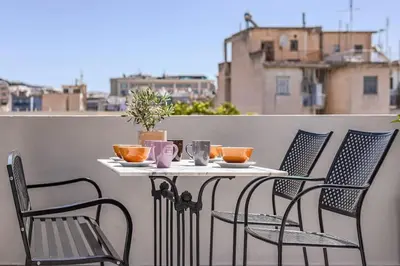 a table and chairs on a balcony with a view of a city at The Meta Stay - Rooftop Access Unique Penthouse in Athens