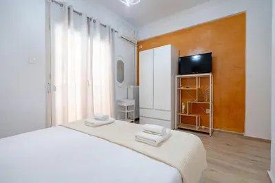 a white bedroom with a bed and a tv at Cozy central apartment for 2 person by MPS in Athens