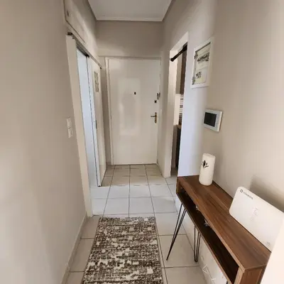 a hallway with a console table and a room with a door at Elite Port in Piraeus