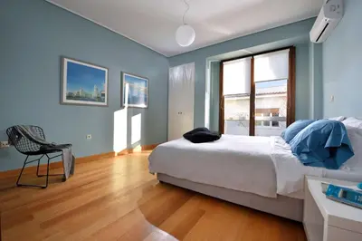 a bedroom with a bed and a chair and a window at Outstanding Athens Apartment Karyatis Luxury Maisonette 3 Bedrooms in Athens