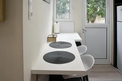 a white table with two chairs and a black rug on it at Apartment in Alimos in Athens