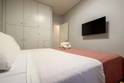 a bedroom with a white bed and a flat screen tv at Spacious and modern one bedroom apartment in Athens