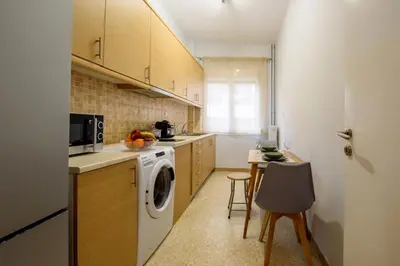 a kitchen with a washing machine and a table at Spacious and modern one bedroom apartment in Athens
